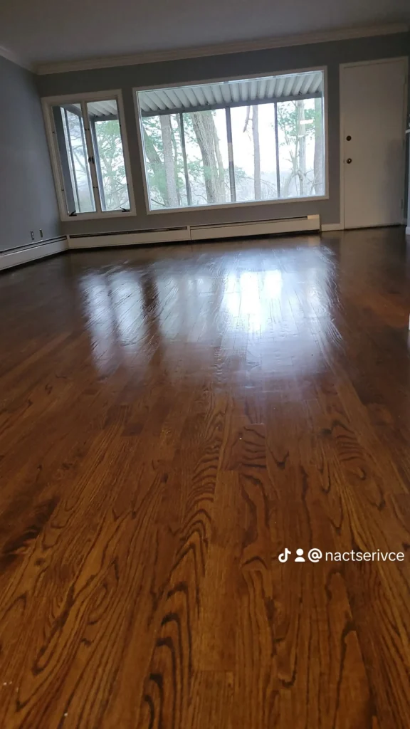 Deep cleaned dark hardwood floors in an empty Airbnb living room with large windows