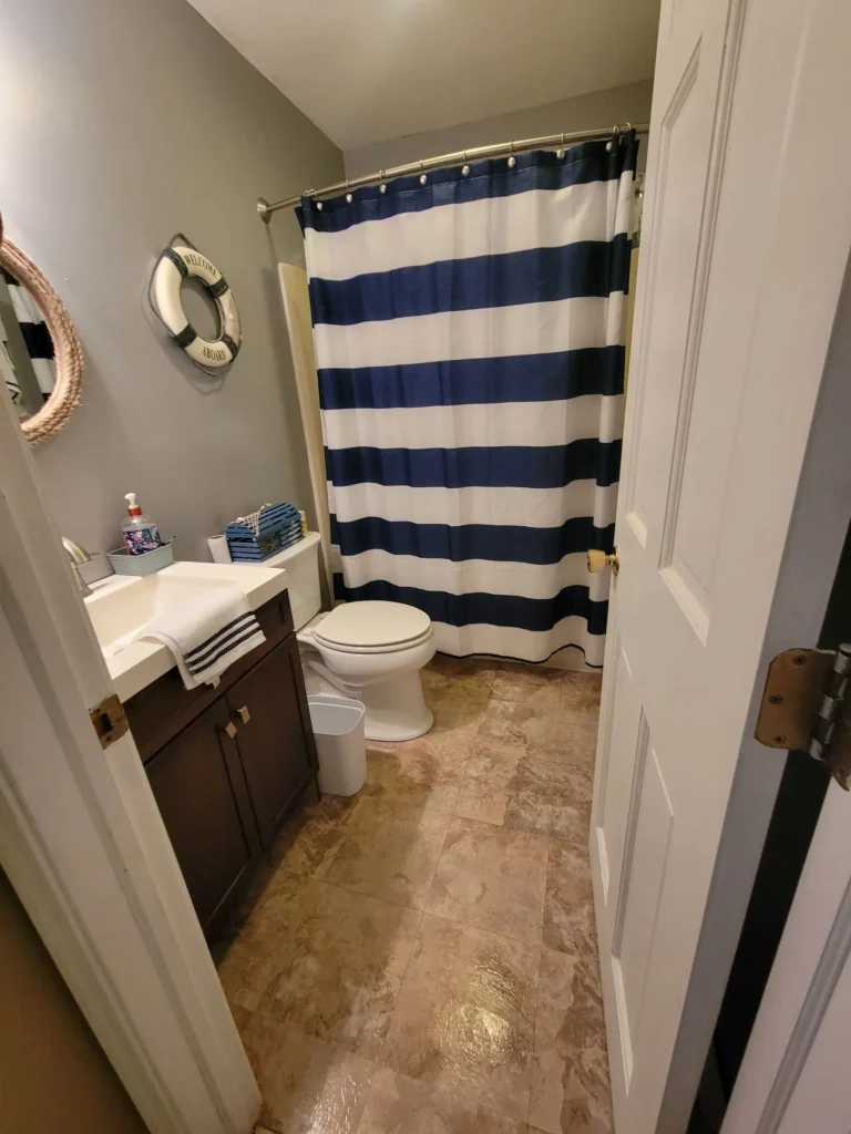 Neat bathroom with striped shower curtain and clean tile floor in Avon, CT