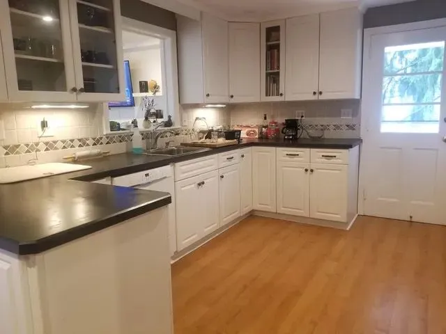 Pristine kitchen with white cabinets and black countertops after deep cleaning in New Britain, CT