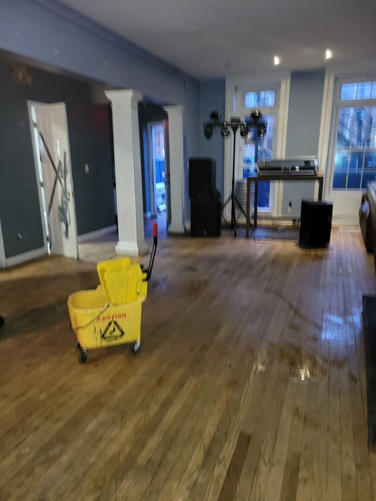 Dirty hardwood floor with mop bucket in event venue during deep cleaning in Bristol, Connecticut