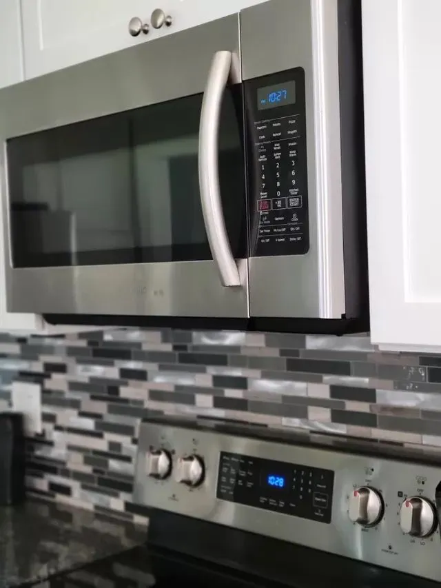 Stainless steel microwave and stove with clean tile backsplash in New Haven kitchen
