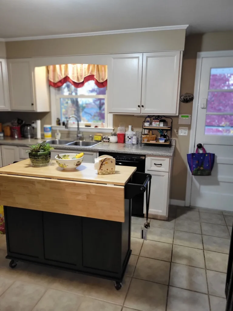 Tidy kitchen with white cabinets, countertop appliances, and island cart after professional cleaning in Southington, Connecticut