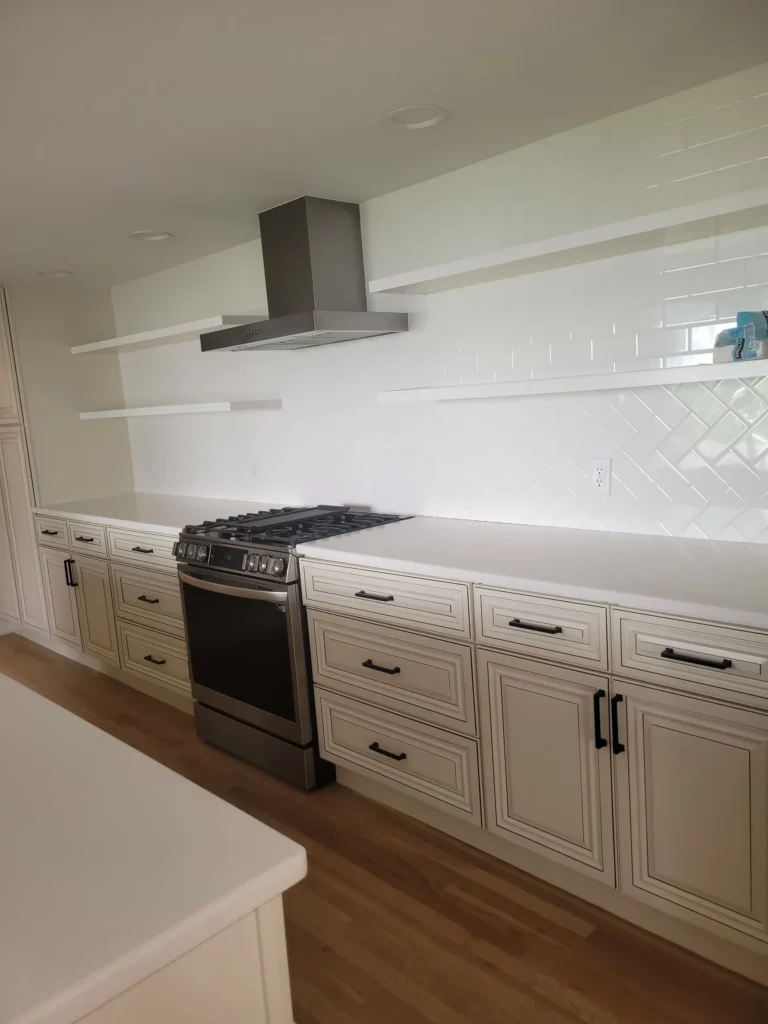 Minimalist kitchen with white cabinetry, range hood, and open shelves after professional cleaning in Bristol, Connecticut