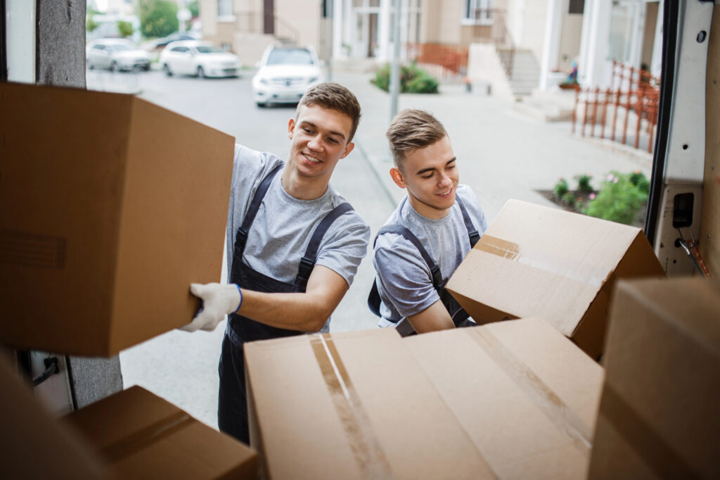 Two professional movers unloading cardboard boxes from a moving van on a residential street in Bristol, Connecticut